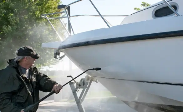 A man spraying a boat with a pressure washer.