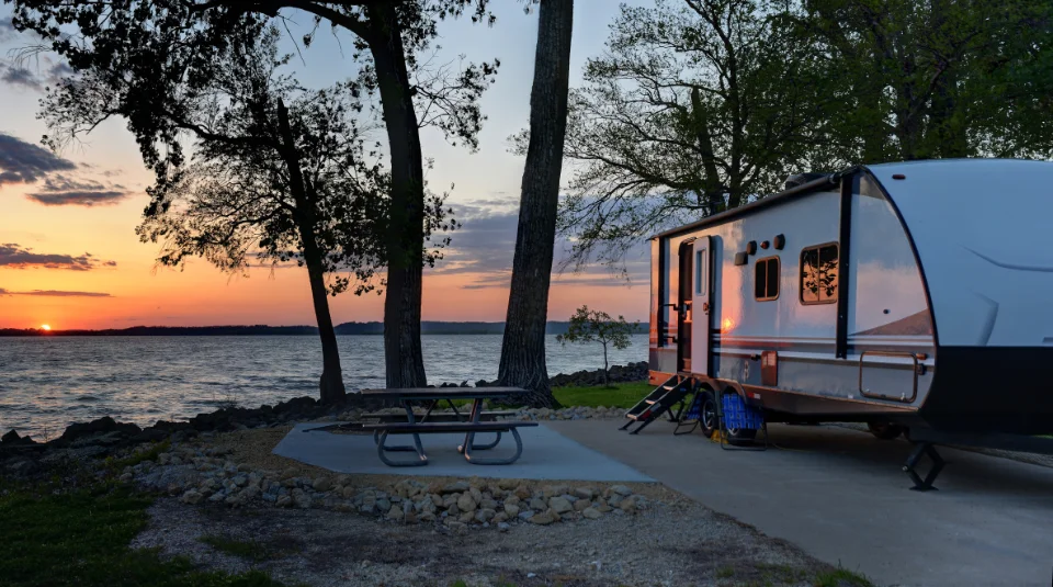 A camper parked next to a lake.